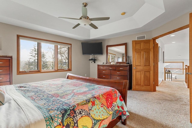 carpeted bedroom featuring ceiling fan and a tray ceiling