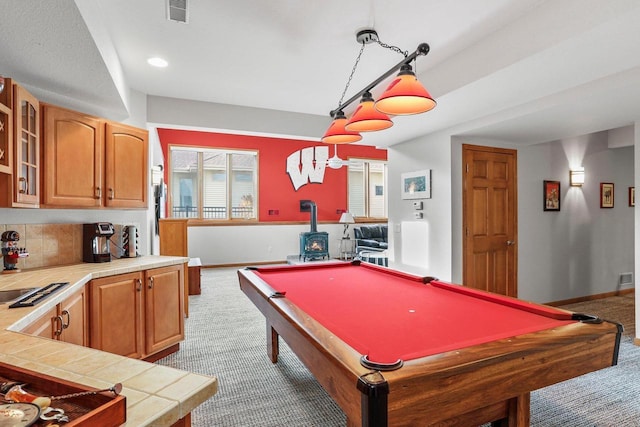 rec room with pool table, light colored carpet, sink, and a wood stove