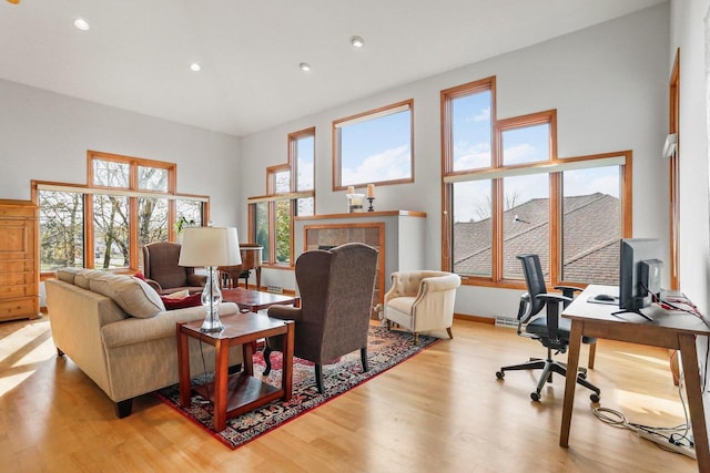 living room featuring a towering ceiling, light wood-type flooring, and a wealth of natural light