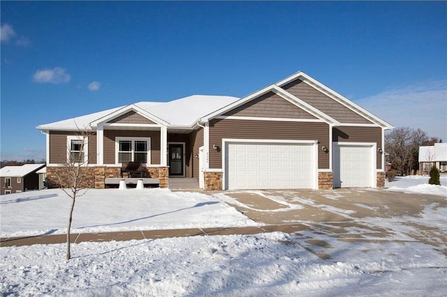 craftsman house with stone siding, an attached garage, and driveway