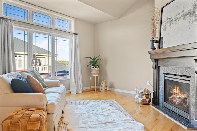 sitting room with light hardwood / wood-style floors, a large fireplace, and a healthy amount of sunlight