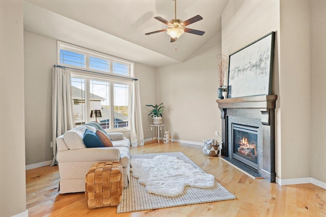 living room with light hardwood / wood-style floors, ceiling fan, and high vaulted ceiling