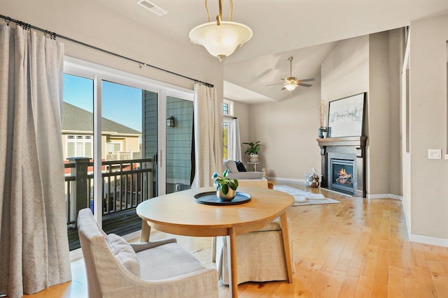 dining area with ceiling fan, light wood-type flooring, and vaulted ceiling