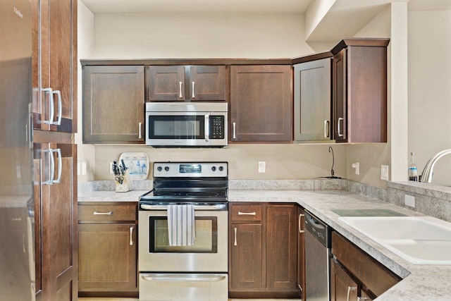 kitchen featuring sink, light stone counters, and appliances with stainless steel finishes