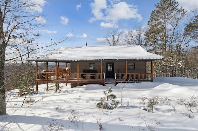 snow covered rear of property featuring a porch