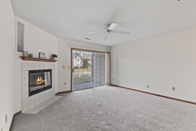 unfurnished living room with a tile fireplace, light colored carpet, and ceiling fan