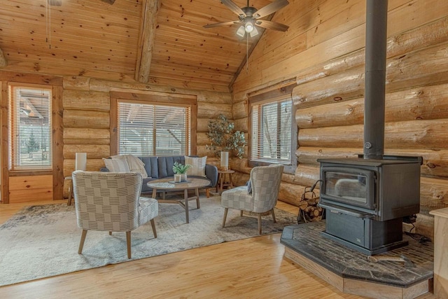 living area featuring high vaulted ceiling, rustic walls, hardwood / wood-style floors, and a wood stove