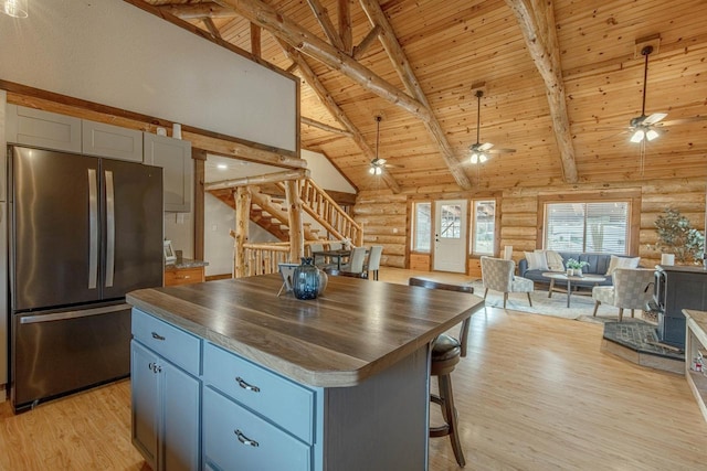 kitchen with beam ceiling, stainless steel fridge, wood ceiling, and log walls