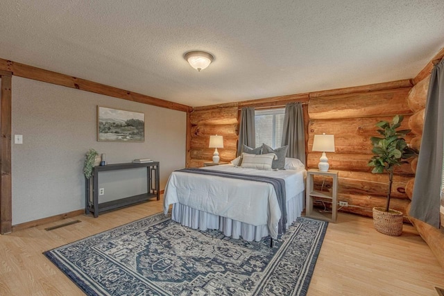 bedroom with hardwood / wood-style floors, a textured ceiling, and log walls