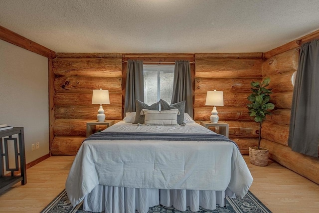 bedroom with a textured ceiling, light wood-type flooring, and rustic walls