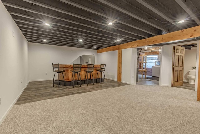 bar featuring dark carpet and stainless steel fridge