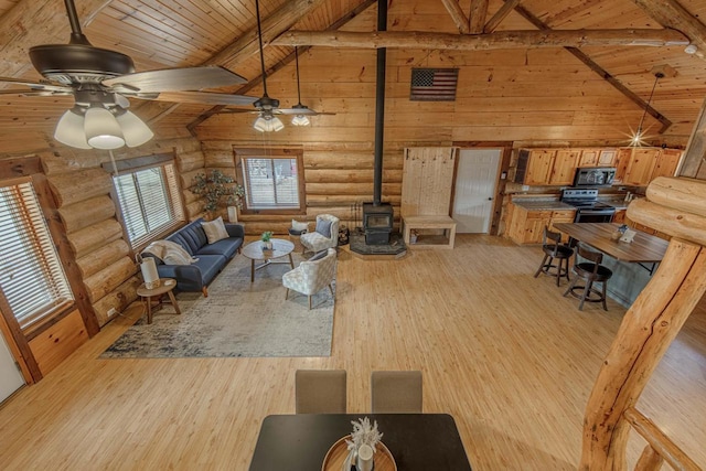 living room with light hardwood / wood-style flooring, log walls, a wood stove, beam ceiling, and wooden ceiling