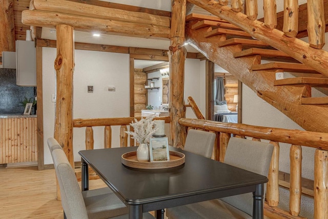 dining area featuring light hardwood / wood-style floors, log walls, and beam ceiling