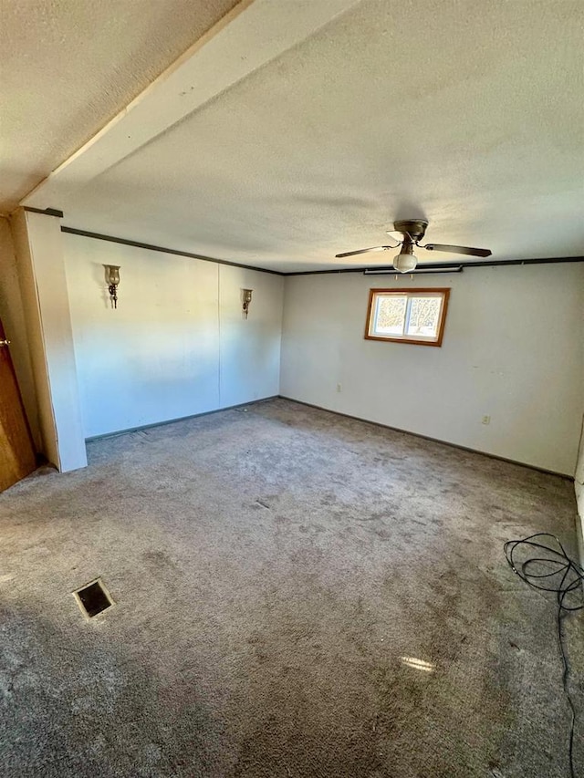 carpeted spare room featuring a textured ceiling and ceiling fan