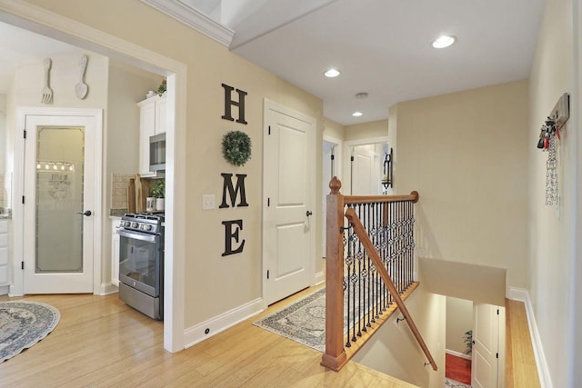 corridor with ornamental molding and light hardwood / wood-style floors