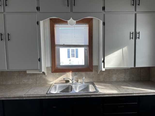 kitchen featuring sink, tile countertops, and white cabinets