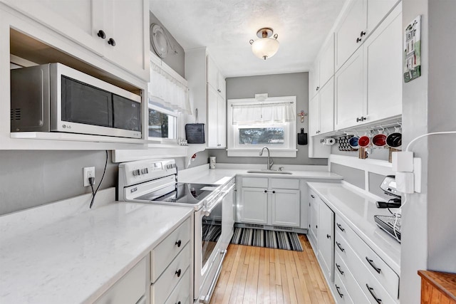 kitchen featuring white appliances, white cabinets, light hardwood / wood-style flooring, and sink