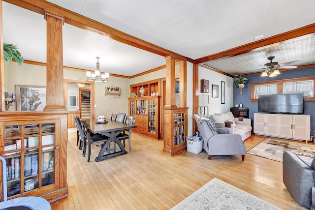 living room featuring ornate columns, light hardwood / wood-style floors, ornamental molding, beam ceiling, and ceiling fan with notable chandelier