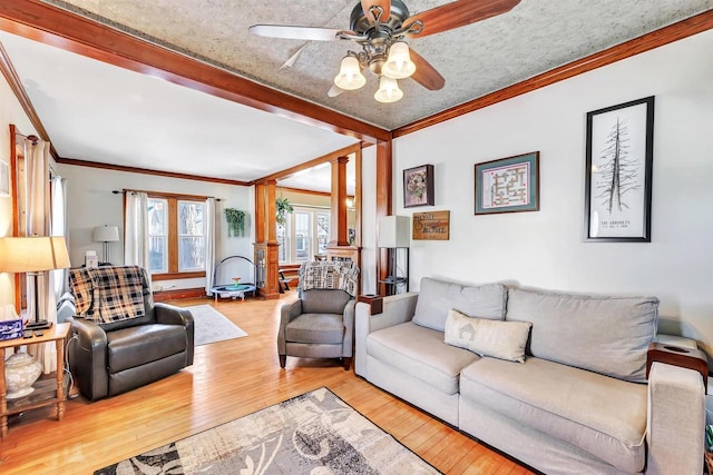 living room with ornamental molding, a textured ceiling, ceiling fan, and light hardwood / wood-style floors