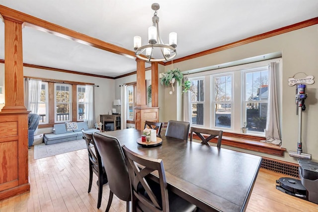 dining area with ornamental molding, light hardwood / wood-style flooring, decorative columns, and a chandelier