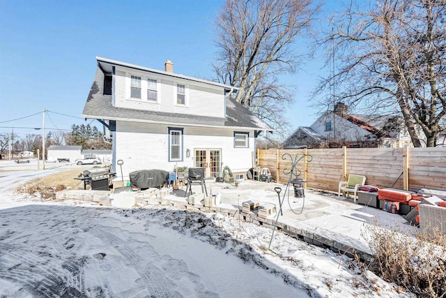 snow covered back of property featuring a patio