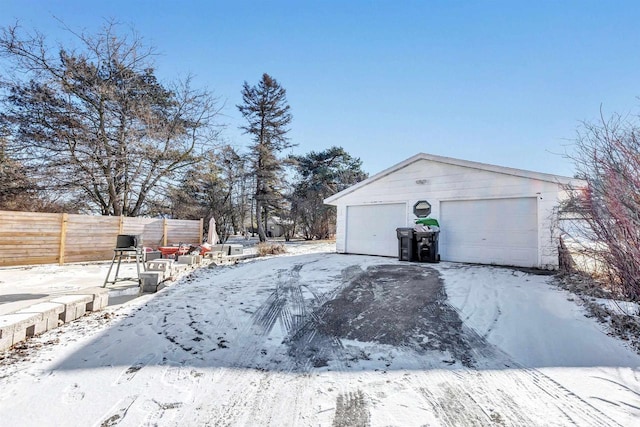 snowy yard featuring a garage and an outbuilding