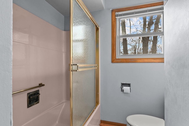 bathroom with toilet and bath / shower combo with glass door