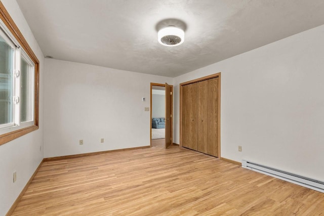 unfurnished bedroom with a baseboard heating unit, light hardwood / wood-style floors, and a closet