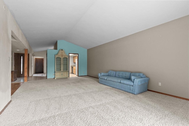 unfurnished living room with vaulted ceiling and carpet flooring