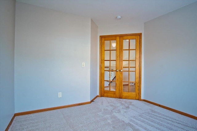 carpeted spare room featuring french doors