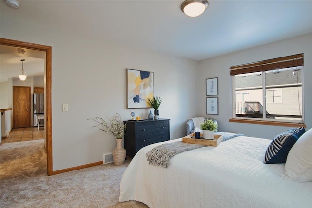 bedroom featuring stainless steel fridge and light colored carpet