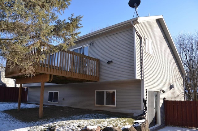 snow covered rear of property featuring a deck