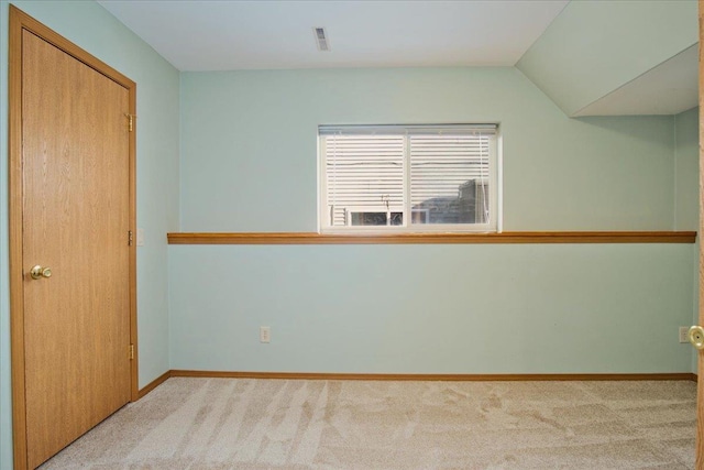 empty room featuring lofted ceiling and light colored carpet