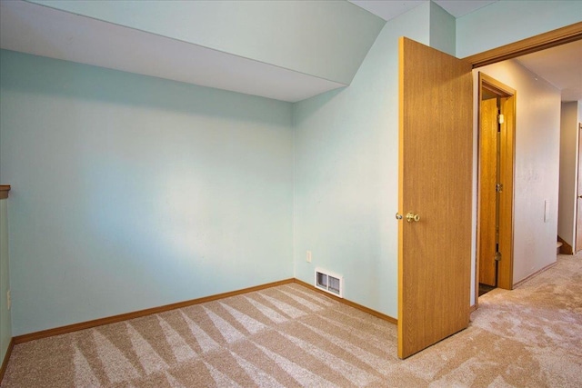 carpeted spare room with vaulted ceiling