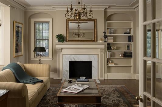 living area with a fireplace, a notable chandelier, dark hardwood / wood-style floors, ornamental molding, and built in shelves