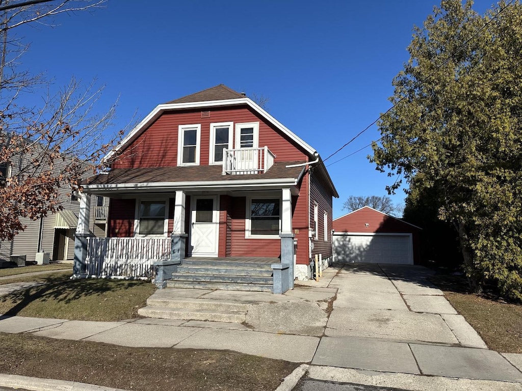 view of front of property featuring a garage, a porch, and an outbuilding