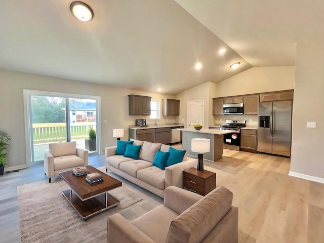 living room with lofted ceiling, light hardwood / wood-style floors, and sink