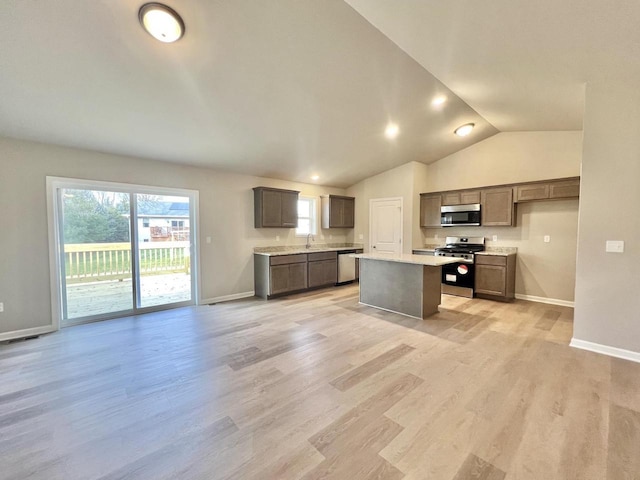 kitchen with stainless steel appliances, sink, vaulted ceiling, light hardwood / wood-style flooring, and a kitchen island