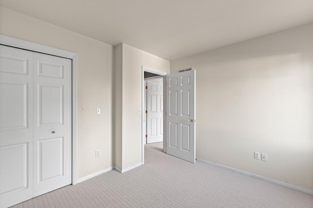 unfurnished bedroom with a closet and light colored carpet