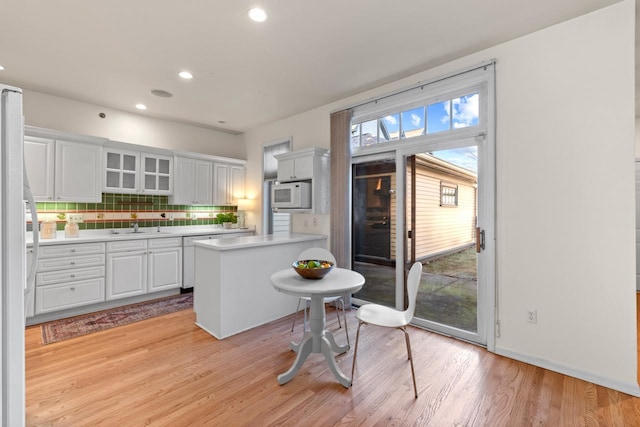 kitchen featuring white cabinetry, light hardwood / wood-style floors, backsplash, white appliances, and sink