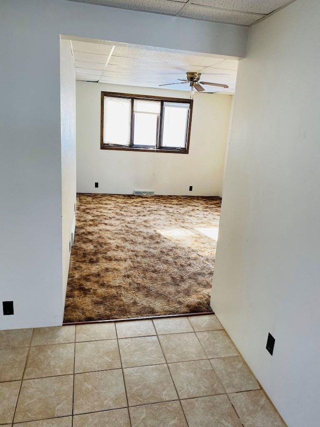 tiled spare room featuring a drop ceiling and ceiling fan