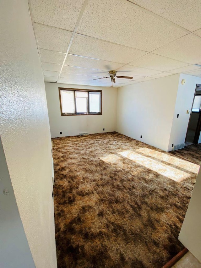 carpeted spare room with a drop ceiling and ceiling fan