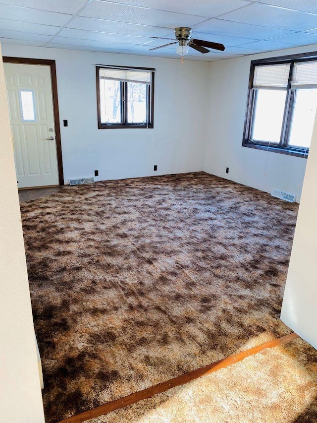 carpeted empty room featuring ceiling fan and a paneled ceiling