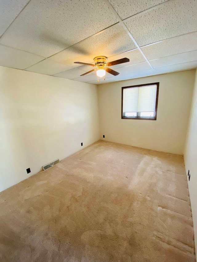 unfurnished room with carpet flooring, a drop ceiling, and ceiling fan