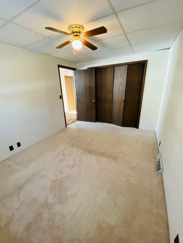 unfurnished bedroom with a closet, ceiling fan, and a paneled ceiling