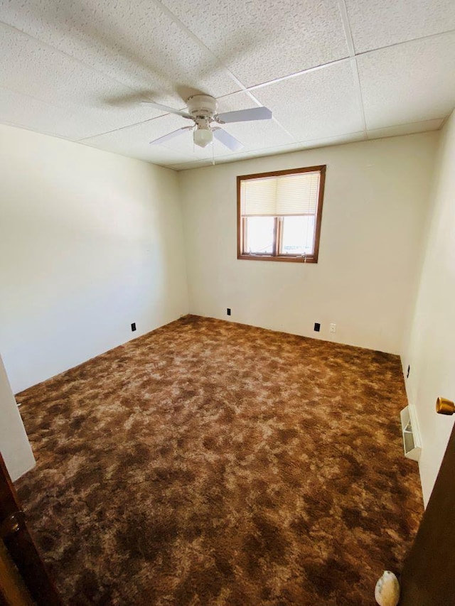 unfurnished room featuring a paneled ceiling, ceiling fan, and carpet