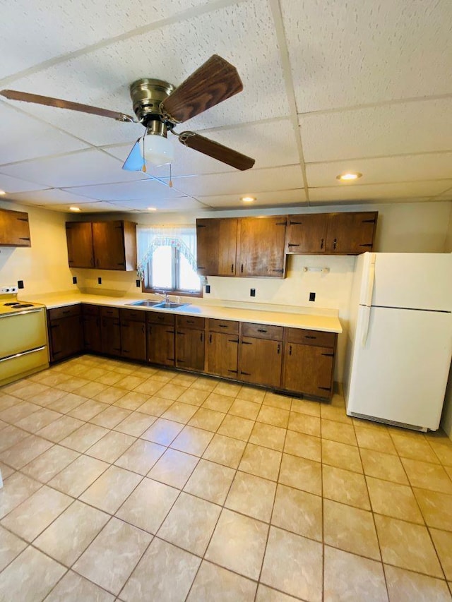 kitchen featuring a paneled ceiling, white fridge, range with electric cooktop, ceiling fan, and sink