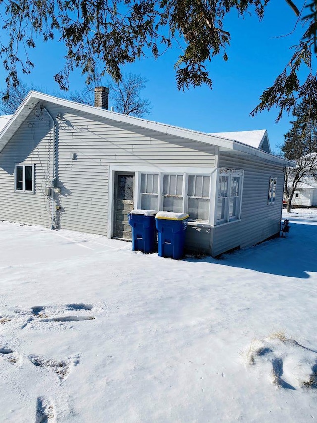 snow covered rear of property featuring central AC unit