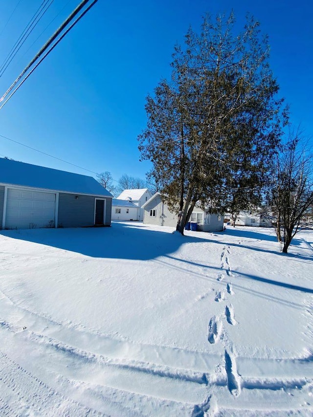 yard covered in snow featuring a garage and an outdoor structure