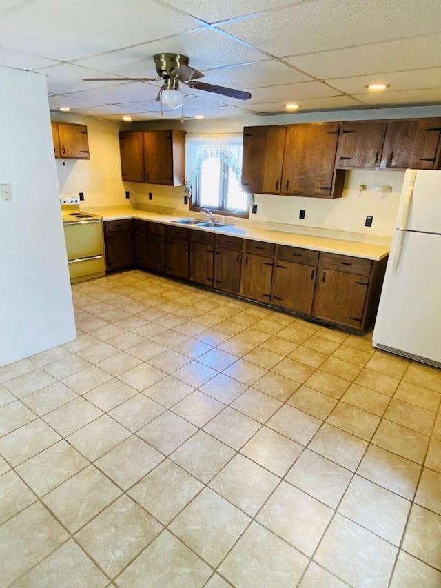 kitchen featuring sink, a drop ceiling, white fridge, ceiling fan, and electric stove